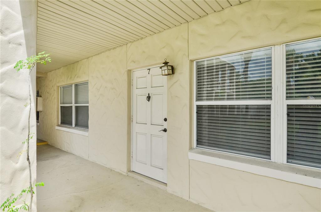 A white front door with a number seven sits on a covered concrete porch — 225 E NEW HAMPSHIRE STREET UNIT 7, ORLANDO, FL