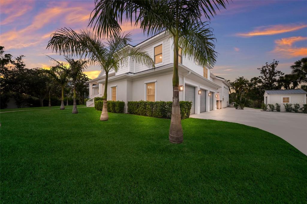 A white two-story house with a three-car garage and palm trees on a grassy lawn — 4678 SILENT CREEK WAY, NOKOMIS, FL