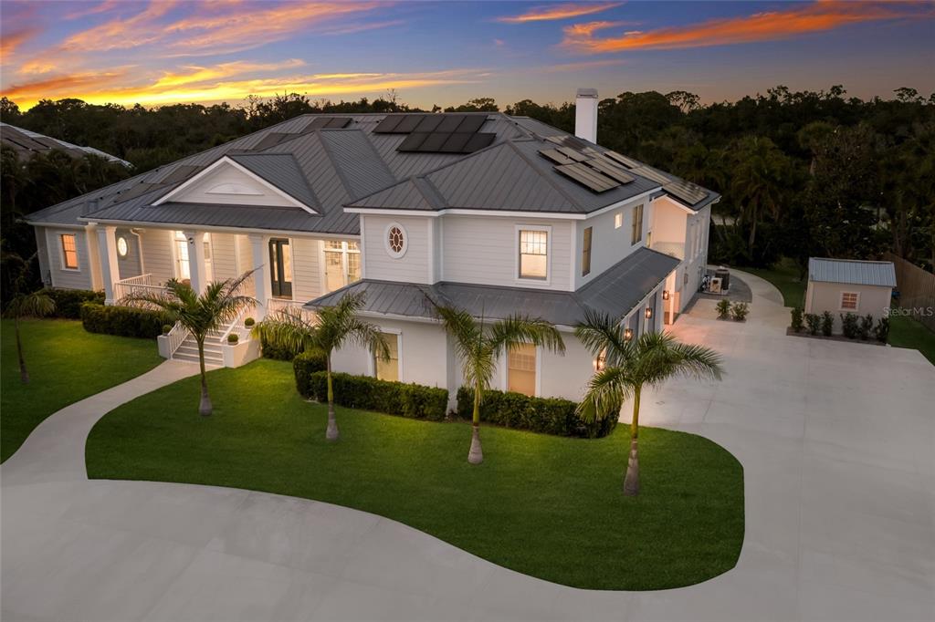 An aerial view of a two-story house with a metal roof, solar panels, and landscaping — 4678 SILENT CREEK WAY, NOKOMIS, FL