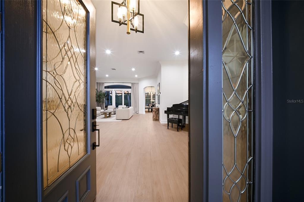 A view through an open front door into a bright, open-concept living area with flooring — 4678 SILENT CREEK WAY, NOKOMIS, FL
