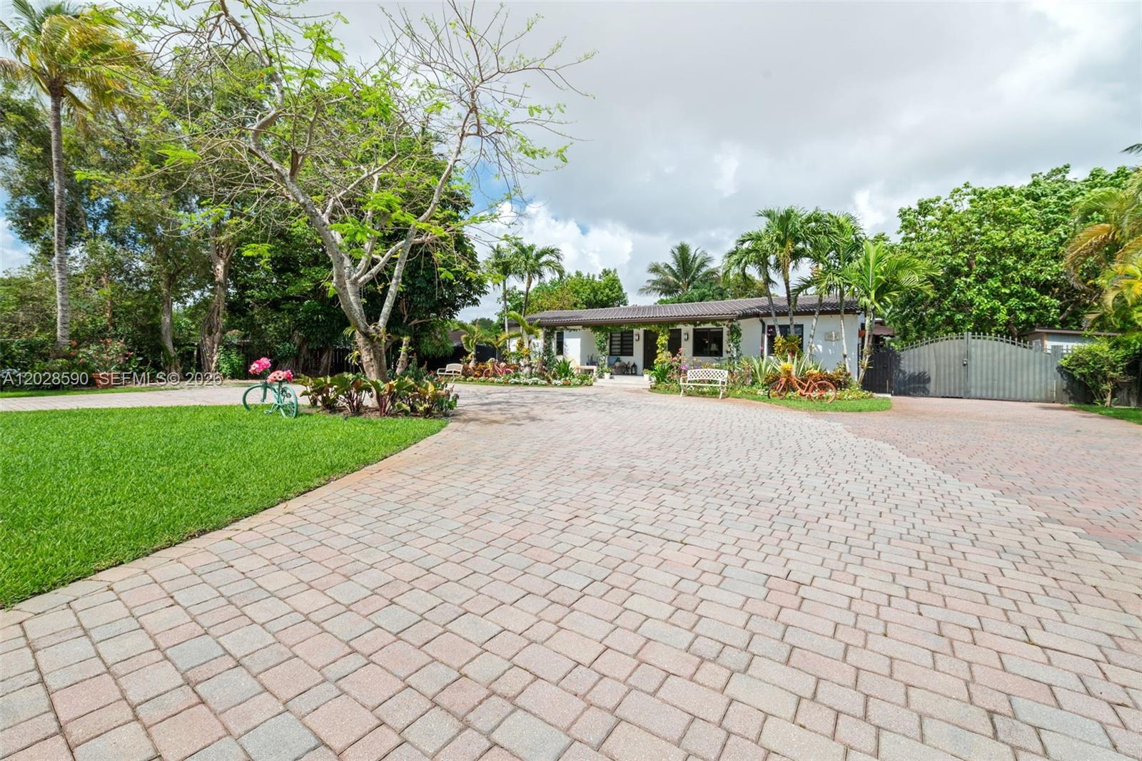 A single-story house with a paved driveway, lush landscaping, and a gated entrance — 13700 N Miami Ave, Miami FL 33168, MIAMI, FL