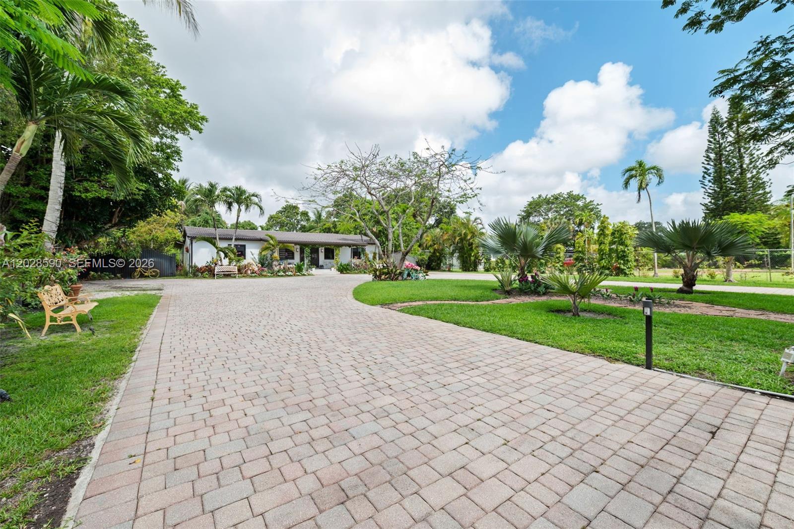 A paved driveway leads to a single-story house surrounded by palm trees and landscaping — 13700 N Miami Ave, Miami FL 33168, MIAMI, FL