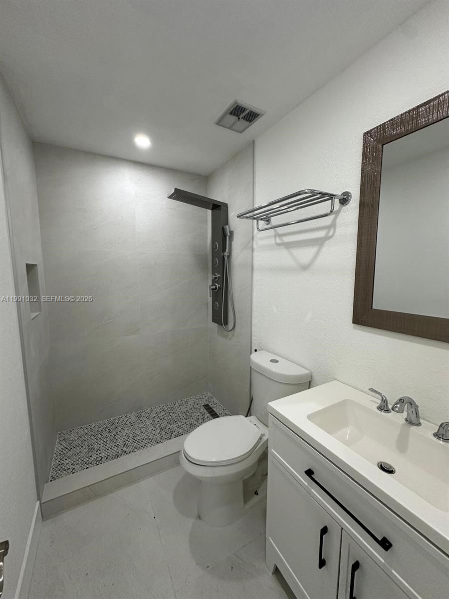 A modern bathroom features a tiled walk-in shower, a white vanity, and a toilet — 20926 SW 124th Ave Rd, Miami FL 33177, MIAMI, FL