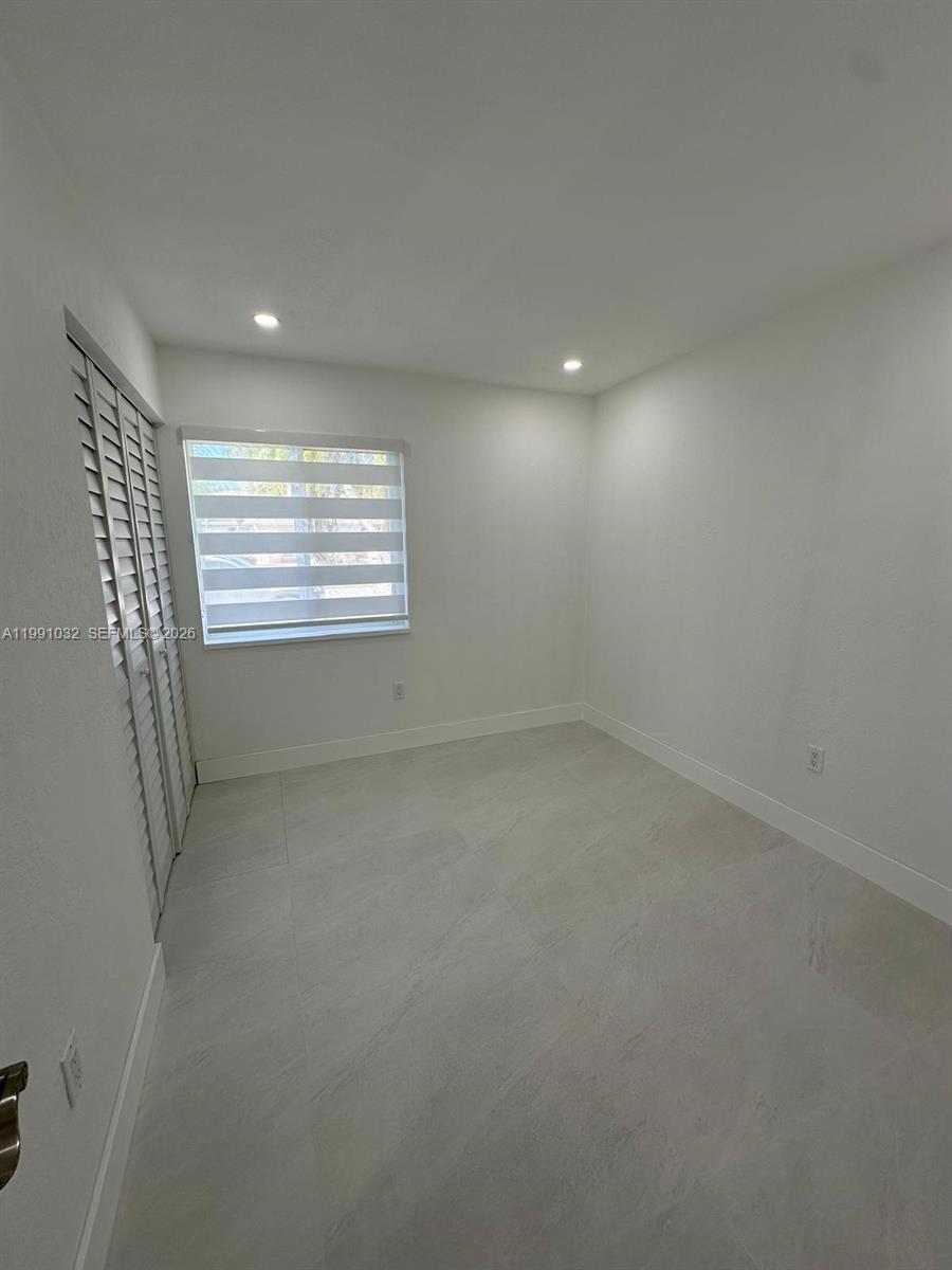 A small, empty room features white walls, light-colored tile flooring, and a window with blinds — 20926 SW 124th Ave Rd, Miami FL 33177, MIAMI, FL