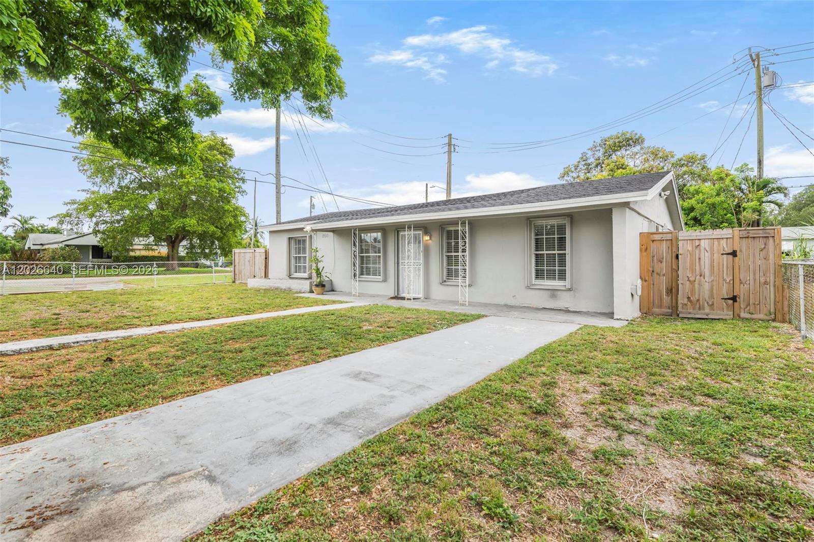 A single-story gray house with a concrete driveway and a wooden fence on the side — 1200 NW 87th St # 1, Miami FL 33147, MIAMI, FL