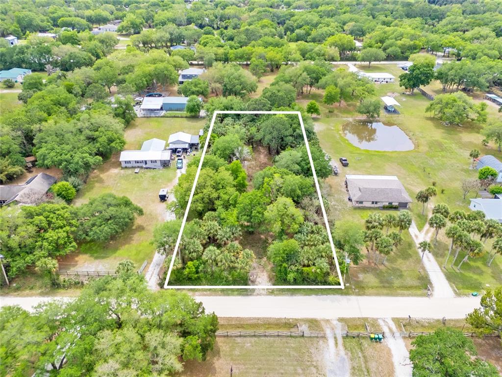 An aerial view shows a rectangular, tree-covered vacant lot outlined in white between two houses — 5175 VACARO AVENUE, COCOA, FL