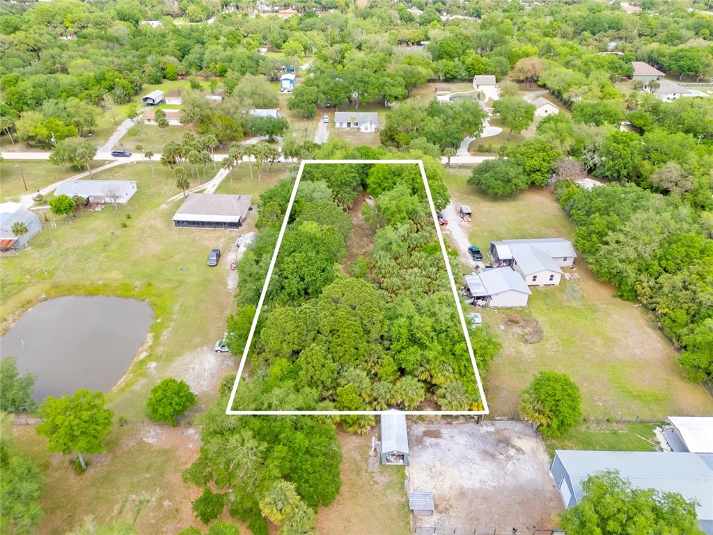 An aerial view shows a rectangular, wooded lot outlined in white amidst a residential area — 5175 VACARO AVENUE, COCOA, FL