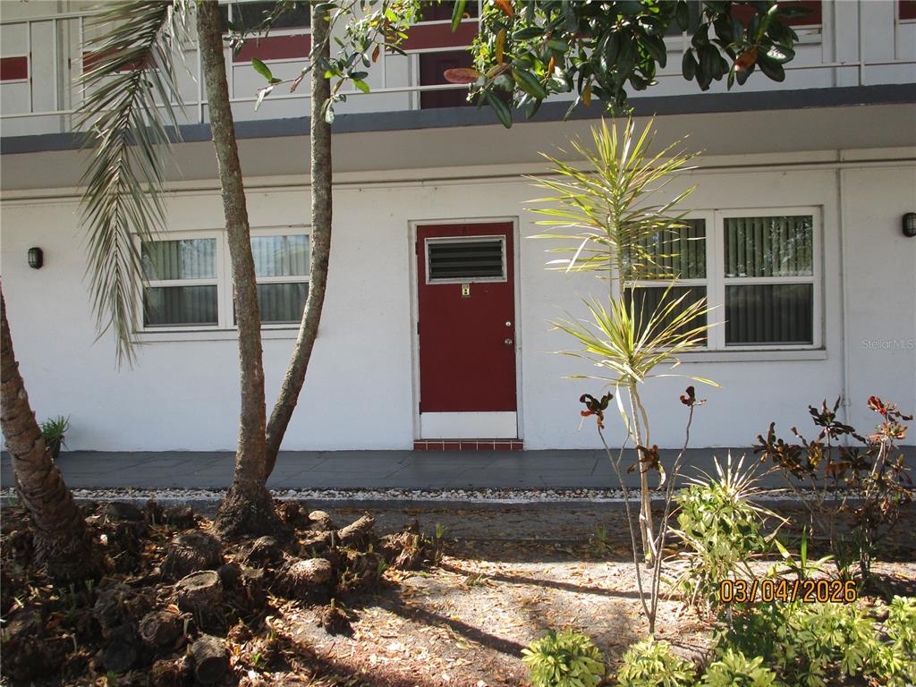 A red front door is centered on the white exterior wall of a multi-story building — 5920 18TH STREET N UNIT 8, ST PETERSBURG, FL