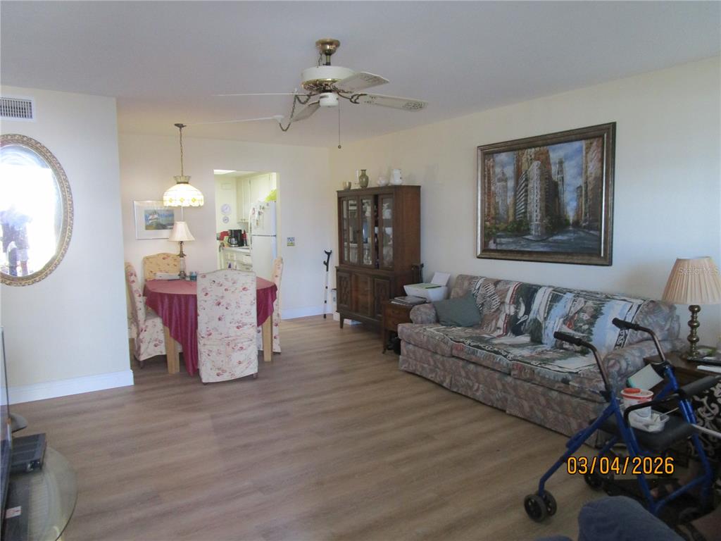 A living and dining room area features light wood-look flooring, a ceiling fan, and furniture — 5920 18TH STREET N UNIT 8, ST PETERSBURG, FL