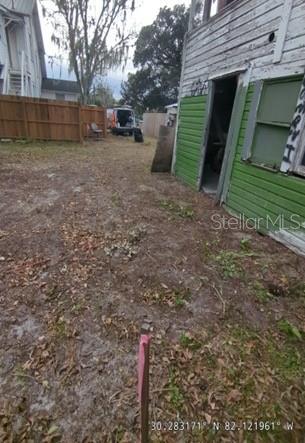 A view of a dirt backyard next to a weathered building with green siding — 47 N 5TH STREET, MACCLENNY, FL