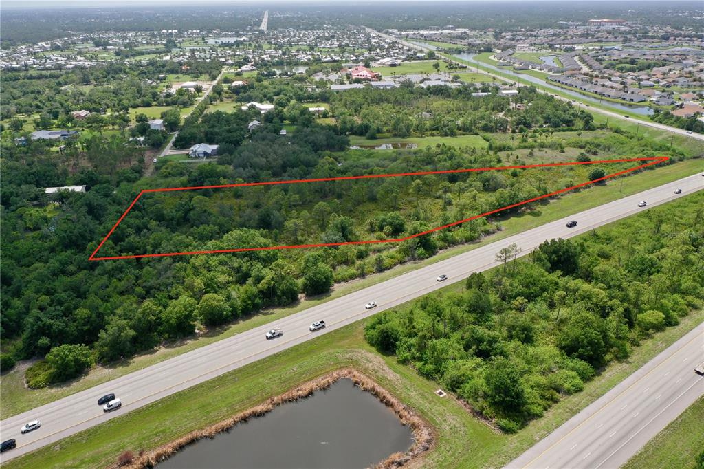An aerial view shows a triangular plot of land outlined in red beside a highway — 24646 TANGELO AVENUE, PORT CHARLOTTE, FL