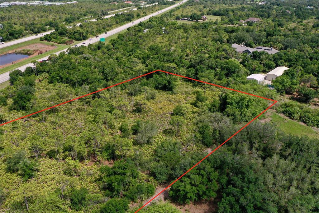 An aerial view shows a rectangular plot of land outlined in red near a highway — 24646 TANGELO AVENUE, PORT CHARLOTTE, FL