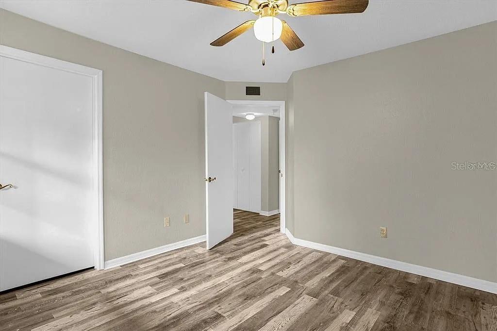 An empty room features light gray walls, wood-look flooring, and a ceiling fan — 7210 WESTPOINTE BOULEVARD UNIT 1323, ORLANDO, FL