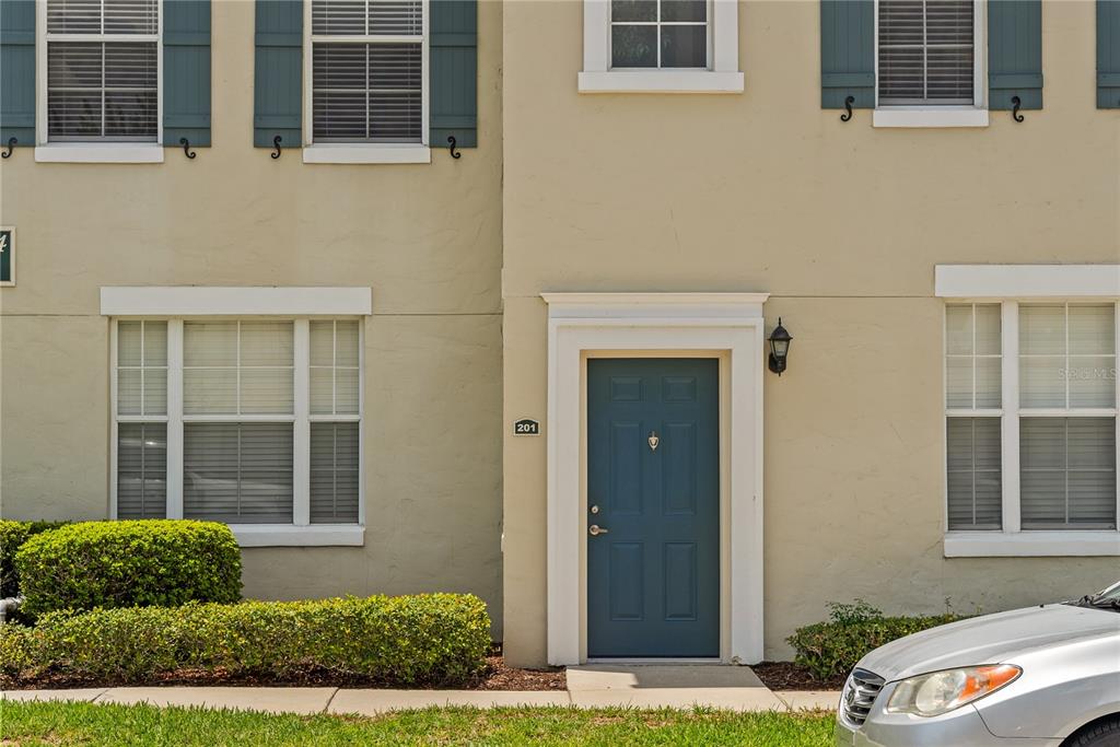 The exterior of a tan townhome features a blue front door labeled 201 — 714 SIENA PALM DRIVE UNIT 201, CELEBRATION, FL