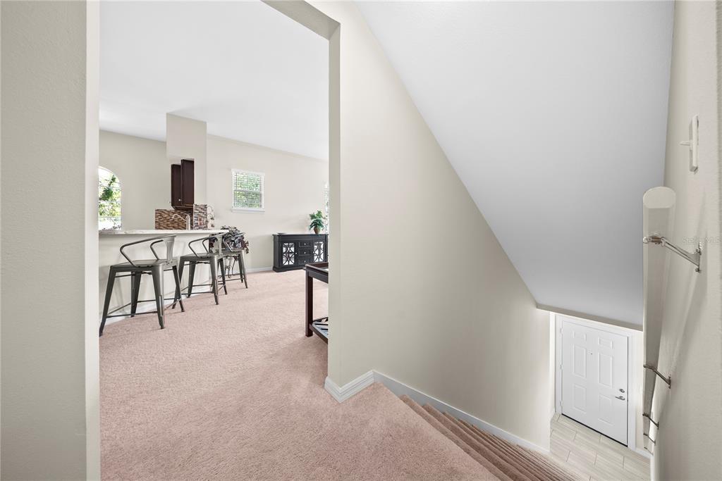 A carpeted landing overlooks a kitchen with a breakfast bar and a lower-level entryway — 714 SIENA PALM DRIVE UNIT 201, CELEBRATION, FL