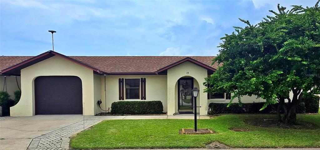 A single-story house with a garage, a front entrance, and a large tree on the lawn — 41 N 20TH ST UNIT 18, HAINES CITY, FL