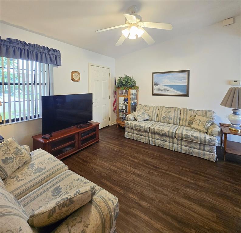 A living room features wood-look flooring, two patterned sofas, a television, and a ceiling fan — 41 N 20TH ST UNIT 18, HAINES CITY, FL