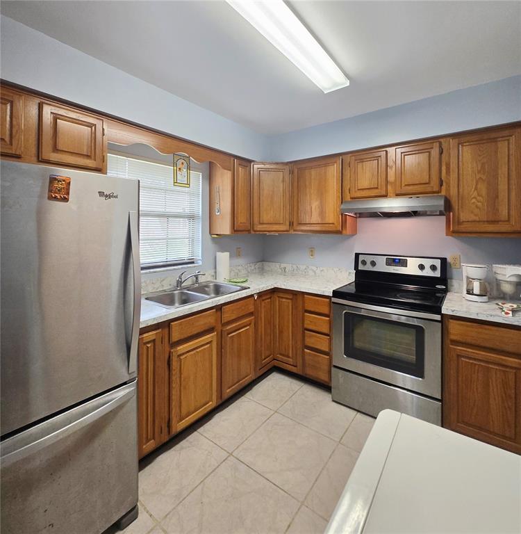A kitchen with wood cabinets, stainless steel appliances, and light-colored countertops and tile flooring — 41 N 20TH ST UNIT 18, HAINES CITY, FL