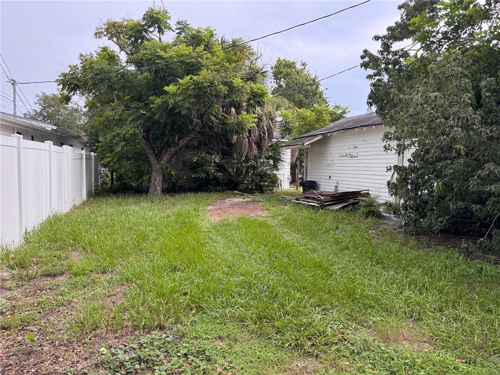 A grassy backyard features a large tree, a white fence, and a small shed — 766 51ST AVENUE N, ST PETERSBURG, FL