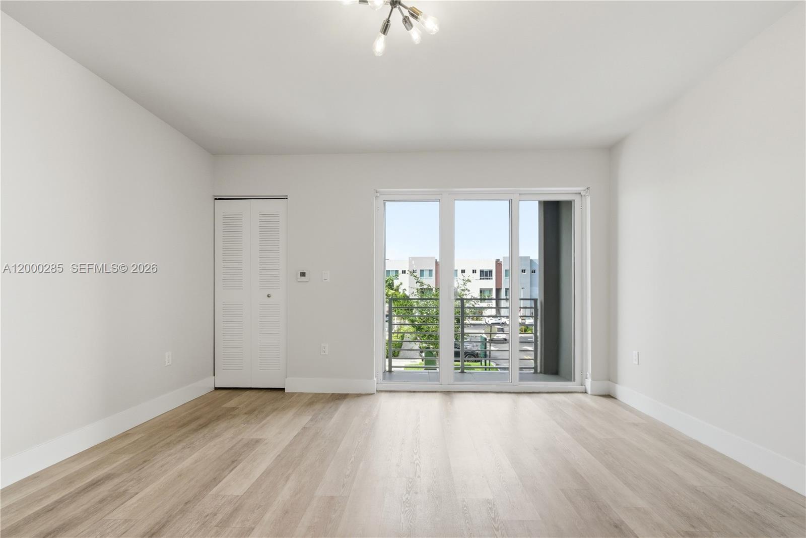 An empty room features light wood-look flooring, white walls, a closet, and a glass balcony door — 2505 NE 193rd St # 4215, Miami FL 33180, MIAMI, FL
