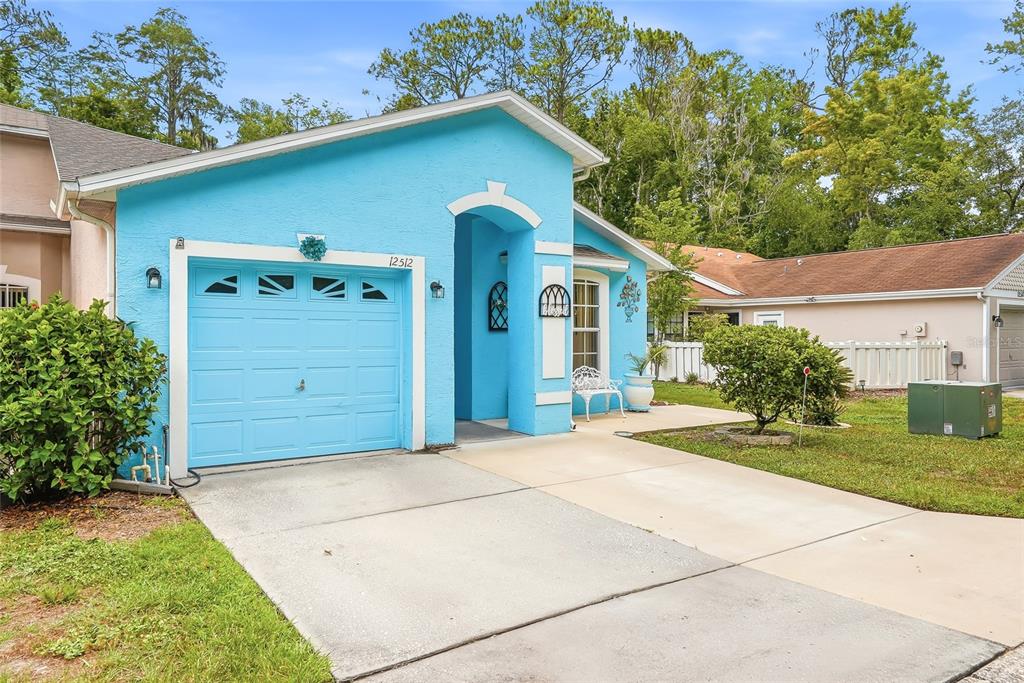 A bright blue single-story house features a one-car garage and a concrete driveway — 12512 HOLLYBROOK LANE, HUDSON, FL