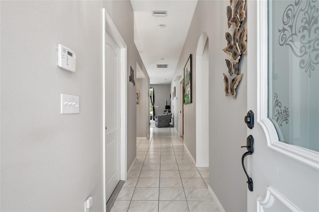 A tiled hallway leads from an entryway toward a living area with light gray walls — 12512 HOLLYBROOK LANE, HUDSON, FL