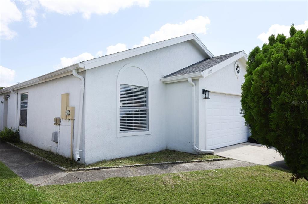 A white stucco house with a single-car garage and a concrete walkway — 5443 BLUEBERRY DRIVE, ORLANDO, FL