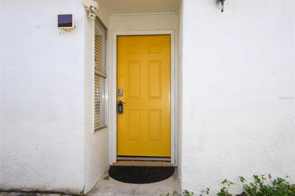 A bright yellow front door is set into a white stucco exterior wall — 5443 BLUEBERRY DRIVE, ORLANDO, FL