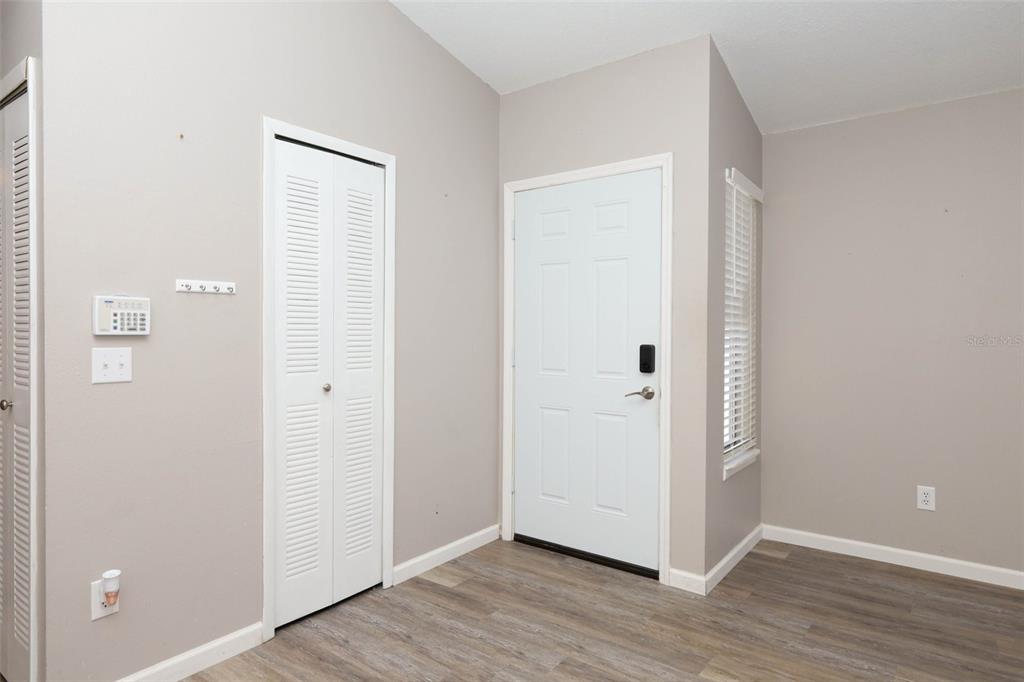 An entryway features light gray walls, wood-look flooring, a white door, and a louvered closet — 5443 BLUEBERRY DRIVE, ORLANDO, FL
