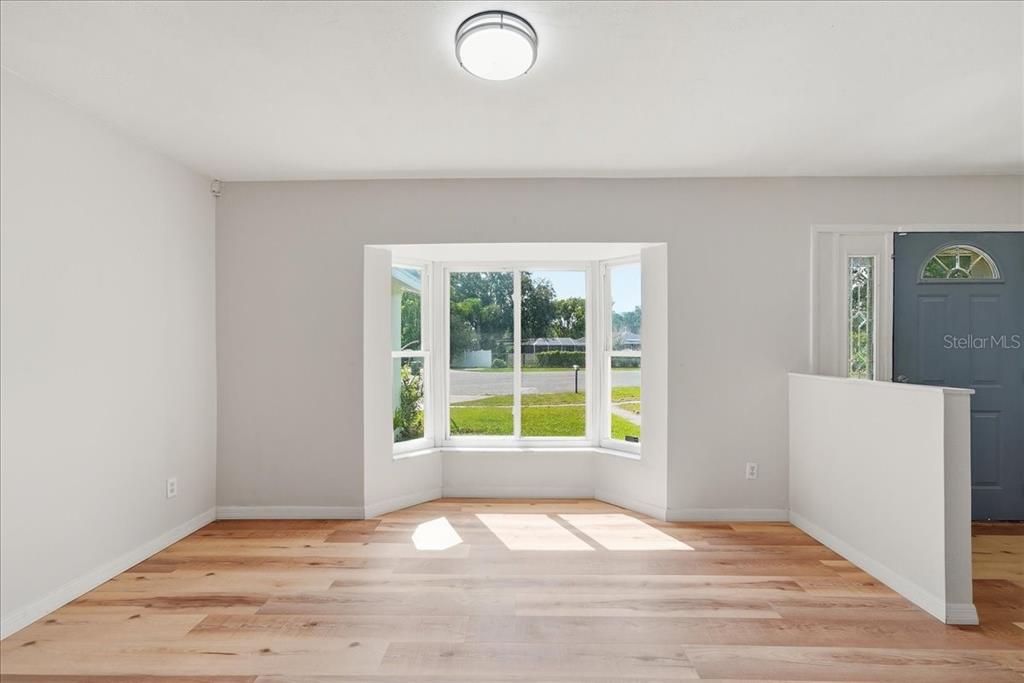 A bright room features light wood flooring, white walls, and a large bay window — 1220 SIENNA COURT, DELTONA, FL