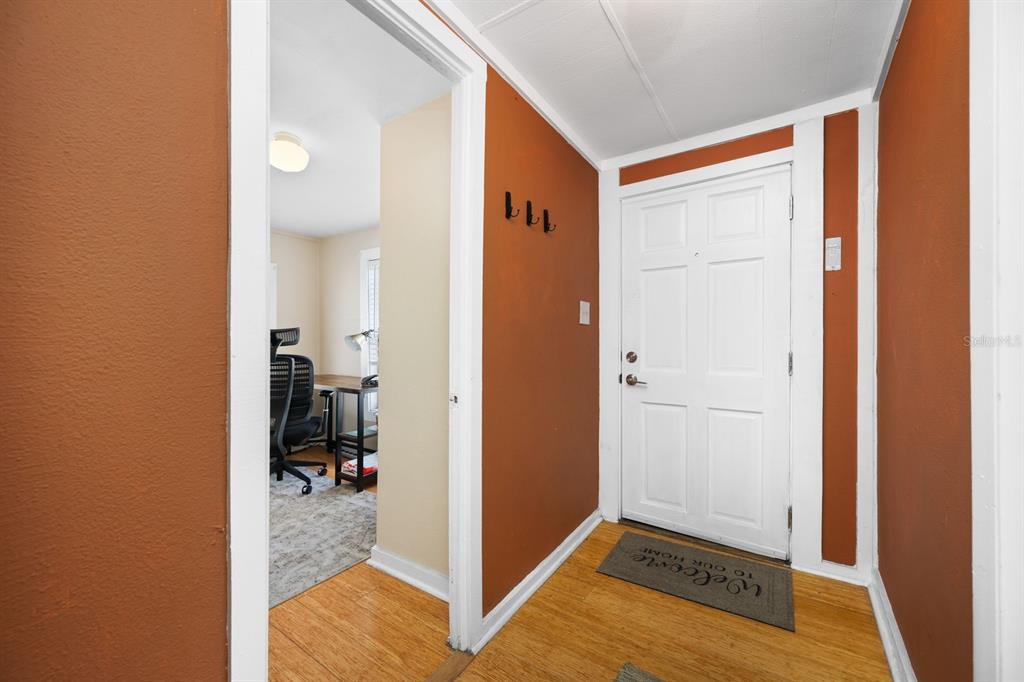 An entryway with hardwood floors, a white door, and a view into an office — 907 18TH AVENUE W, PALMETTO, FL