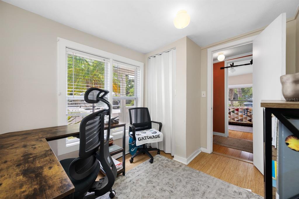 A home office features a wood-grain desk, two black mesh chairs, and a window view — 907 18TH AVENUE W, PALMETTO, FL