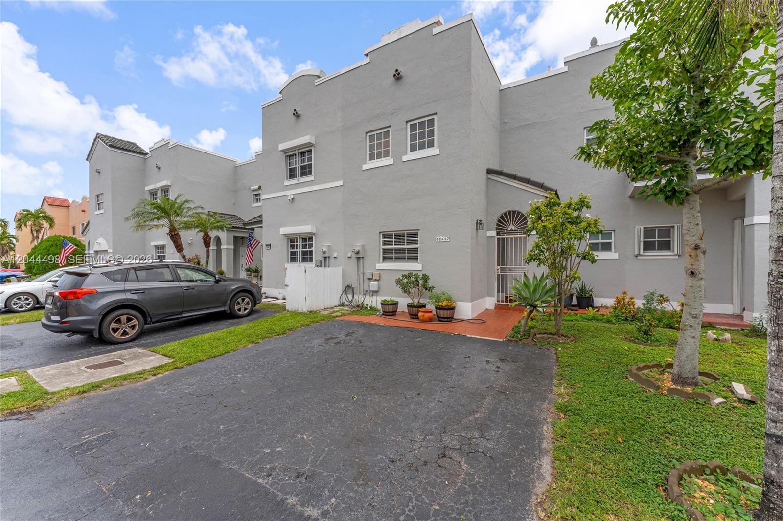 A gray two-story townhouse with a paved driveway and a small front yard — 12427 NW 7th Ln, Miami FL 33182, MIAMI, FL