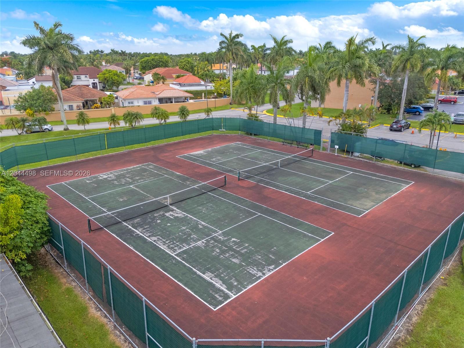 An aerial view of two outdoor tennis courts enclosed by green chain-link fencing — 12427 NW 7th Ln, Miami FL 33182, MIAMI, FL