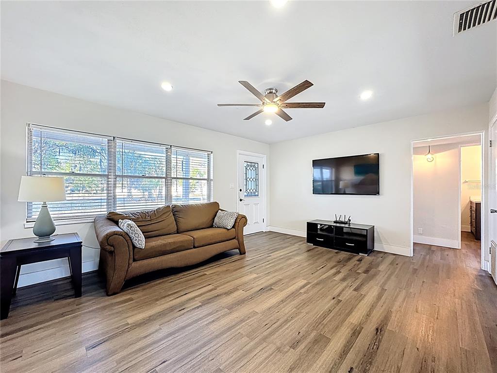 A living room features a brown sofa, a wall-mounted television, and wood-look flooring — 512 N LAKEMONT AVENUE, WINTER PARK, FL