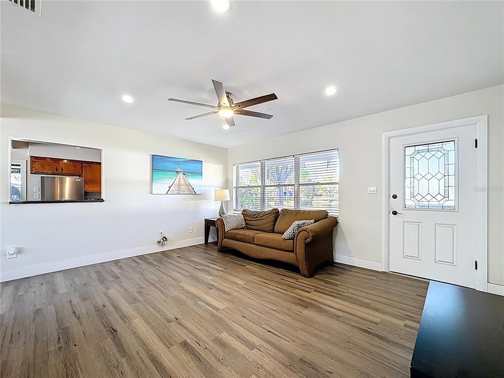 A living room features wood-look flooring, a brown sofa, and a view into the kitchen — 512 N LAKEMONT AVENUE, WINTER PARK, FL