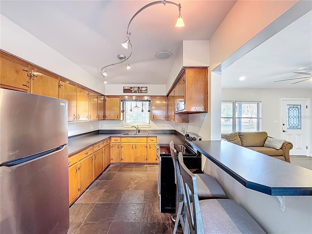 A kitchen with wood cabinets, dark countertops, slate flooring, and a breakfast bar — 512 N LAKEMONT AVENUE, WINTER PARK, FL