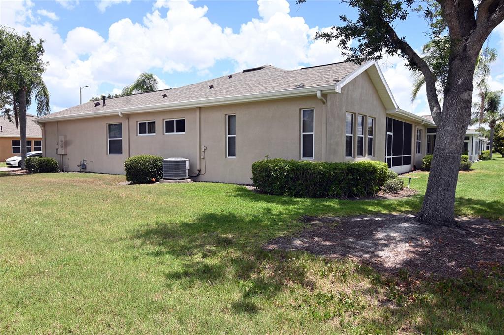A side view of a beige stucco house with a screened-in porch and lawn — 2294 SIFIELD GREENS WAY UNIT 2294, SUN CITY CENTER, FL