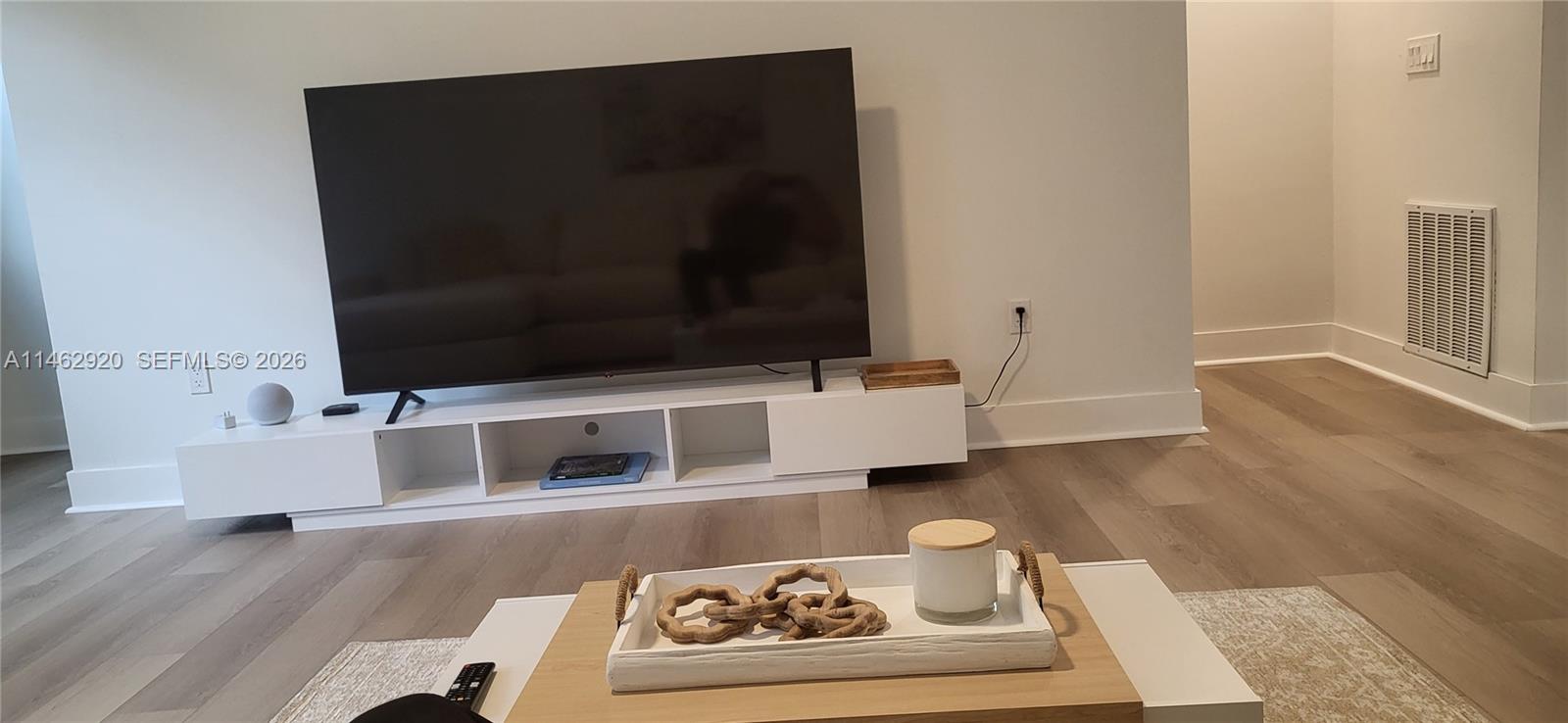 A living room features a large television on a white media console and light wood flooring — 2069 S Ocean Dr, Hallandale Beach FL 33009, HALLANDALE BEACH, FL