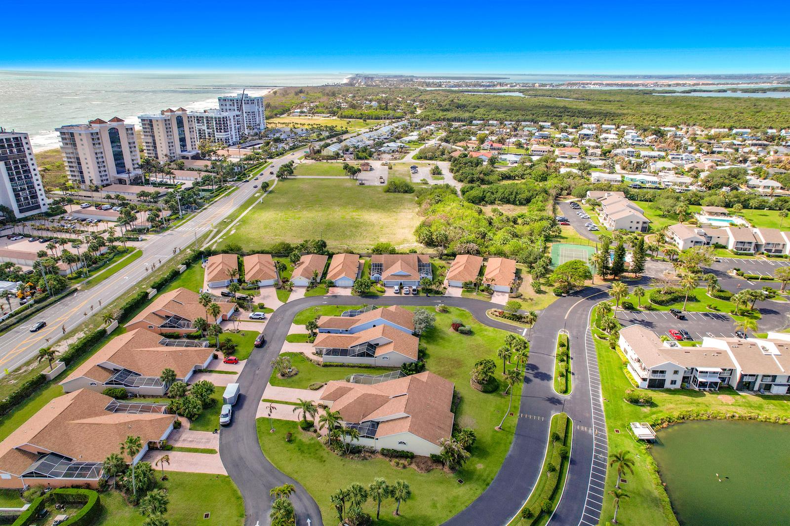 An aerial view shows a residential community with houses, a pond, and nearby coastal buildings — 208 River Walk, Fort Pierce FL 34949, FORT PIERCE, FL