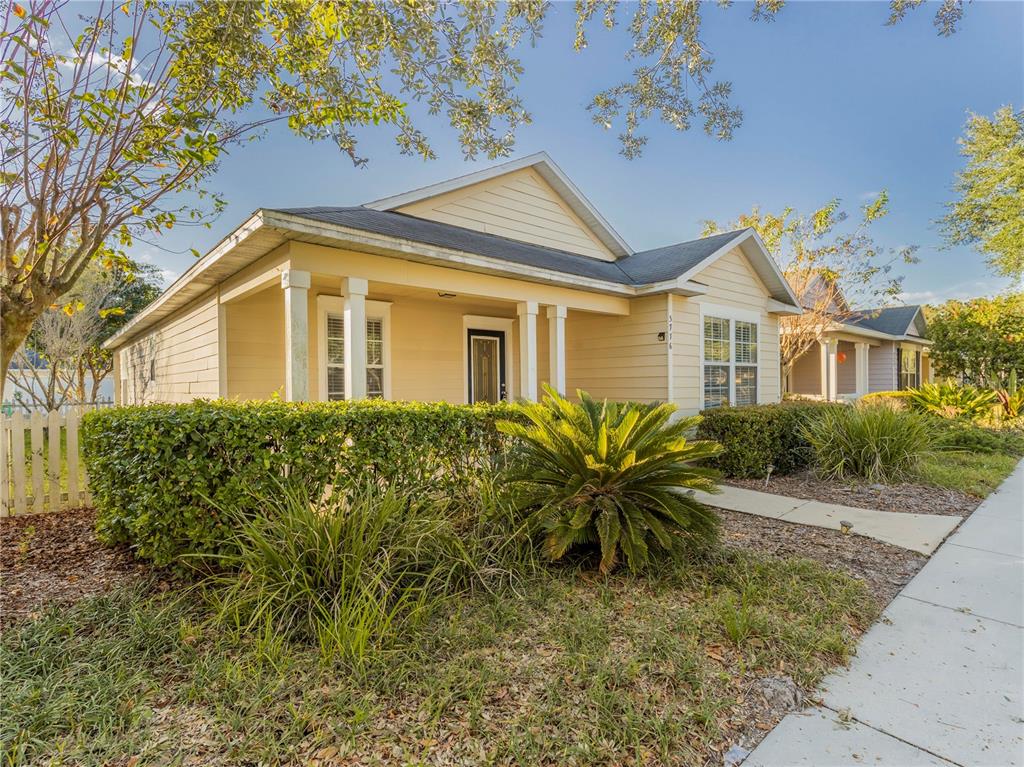 A single-story house with beige siding, a front porch, and a manicured hedge — 3776 NW 26TH TERRACE, GAINESVILLE, FL