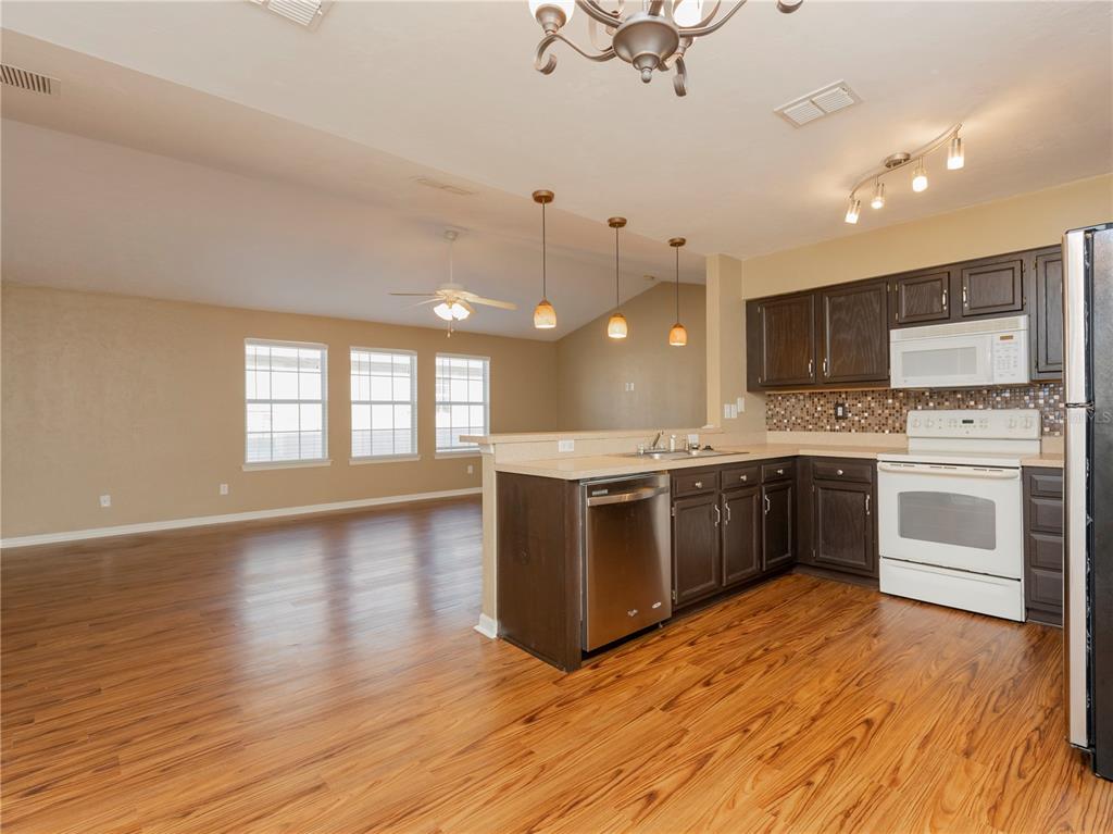 A kitchen with dark wood cabinets and stainless steel appliances opens to a living area — 3776 NW 26TH TERRACE, GAINESVILLE, FL