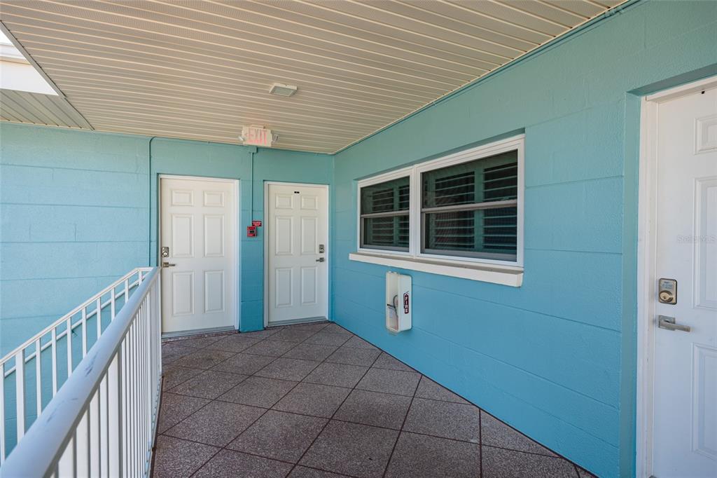 An exterior walkway features blue walls, three white doors, and a window — 6000 2ND STREET E UNIT 6, ST PETE BEACH, FL
