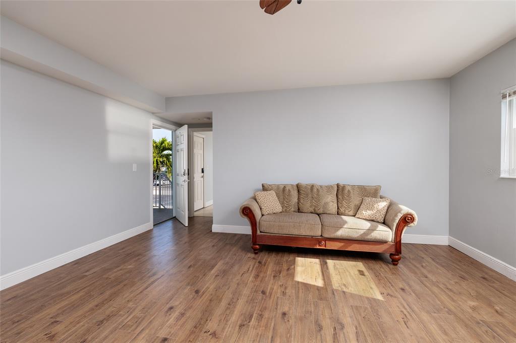 A living room with light gray walls, wood-look flooring, and a tan sofa — 6000 2ND STREET E UNIT 6, ST PETE BEACH, FL