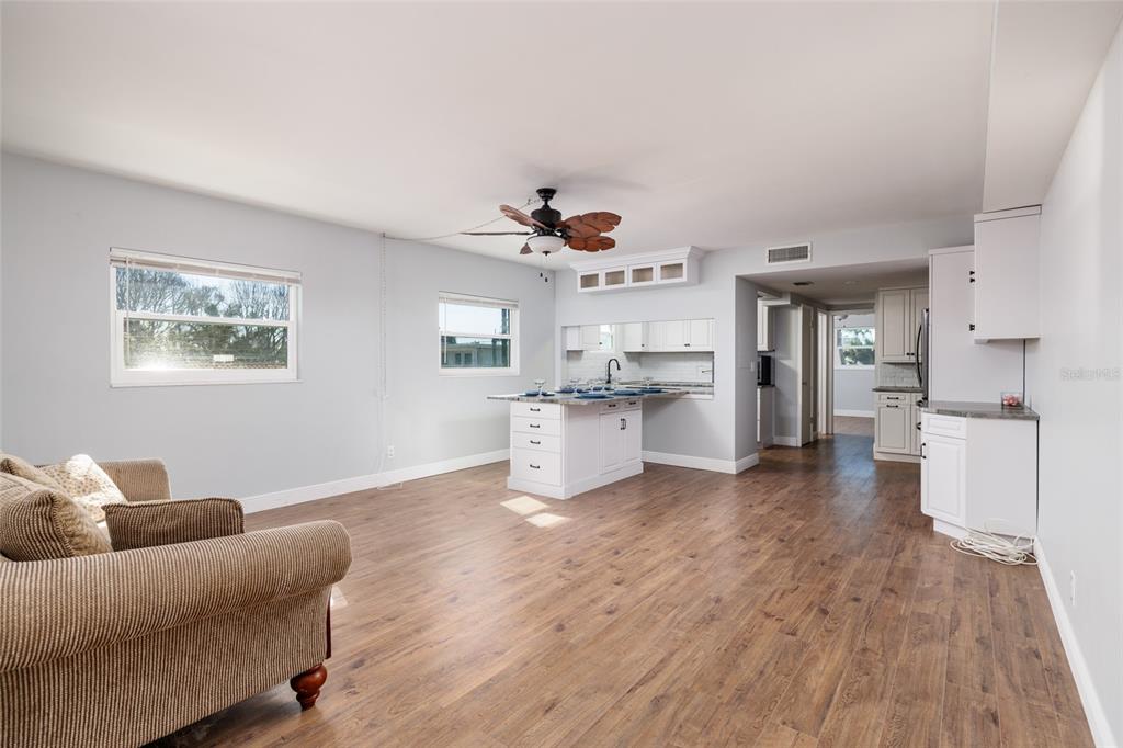 A living room with wood-look flooring, a kitchen island, and white cabinetry — 6000 2ND STREET E UNIT 6, ST PETE BEACH, FL