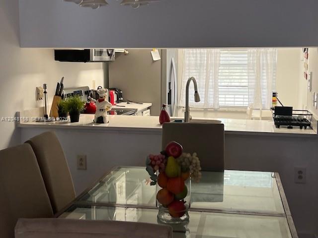 A dining area with a glass table and fruit centerpiece overlooks a kitchen with white counters — 1207 Bahama Bnd # E2, Coconut Creek FL 33066, COCONUT CREEK, FL