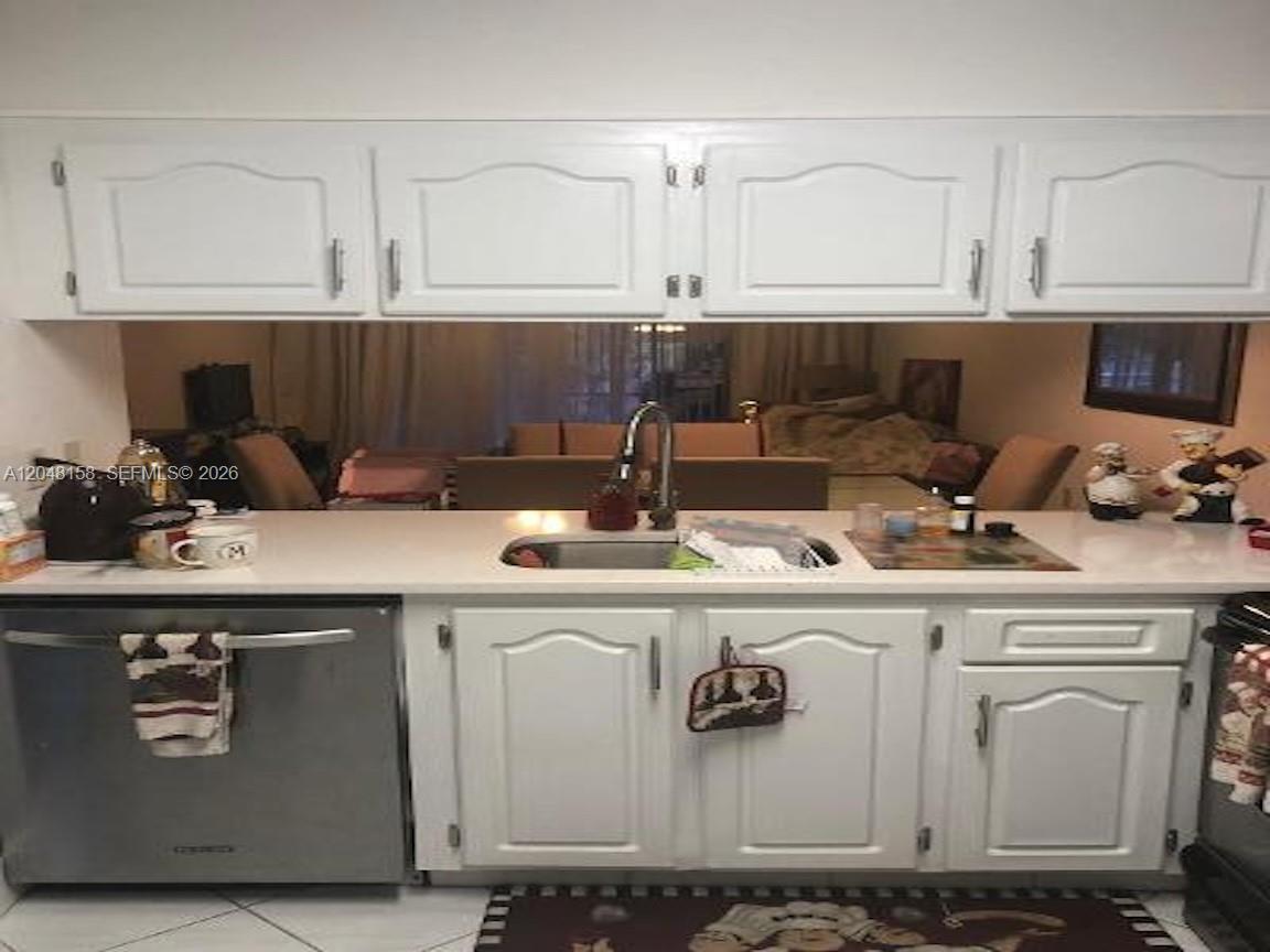 A kitchen features white cabinets, a stainless steel dishwasher, and a white countertop — 1207 Bahama Bnd # E2, Coconut Creek FL 33066, COCONUT CREEK, FL