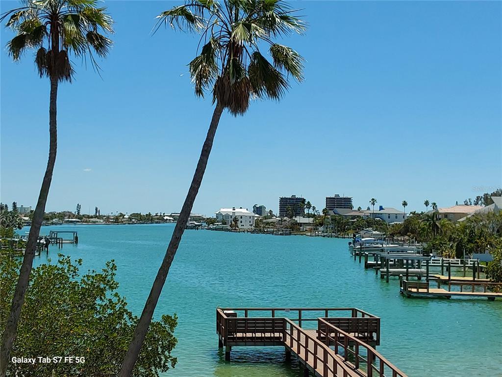 A view of a turquoise waterway with a wooden dock and palm trees — 8565 W GULF BOULEVARD UNIT 11S, ST PETERSBURG, FL