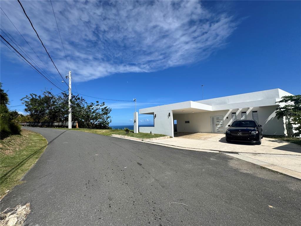 A modern white house with a carport sits beside a road overlooking the ocean — El Cocal Country Club BO. CAMINO NUEVO UNIT 2, YABUCOA, PR