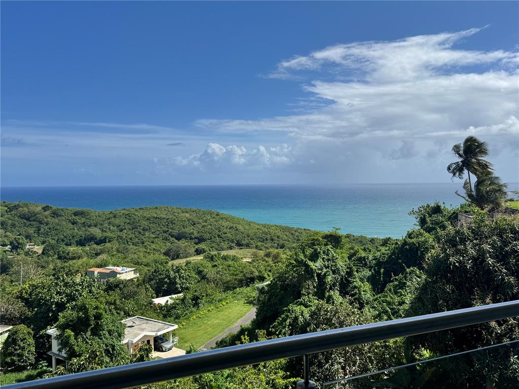 A view from a balcony overlooking a lush green landscape and the ocean — El Cocal Country Club BO. CAMINO NUEVO UNIT 2, YABUCOA, PR